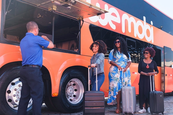 Imagem de família de três integrantes despachando seus pertences no ônibus da wemobi e sorrindo