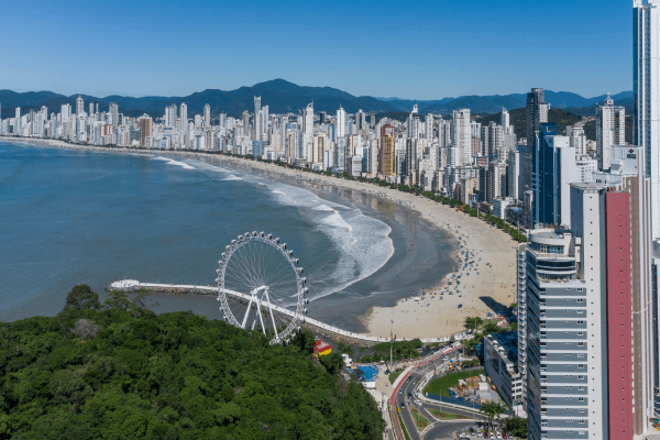Imagem de Balneário Camboriú vista de cima. Respectivamente, seus prédios, praia e roda gigante.